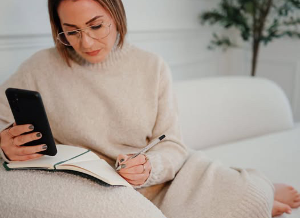 Caroline Burnell, Counsellor, sitting on a sofa, looking at a mobile phone.