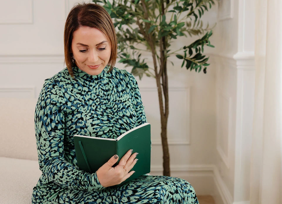 Caroline Burnell, Counsellor, sitting on a sofa and looking down at a notebook.