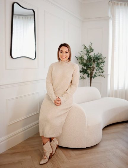 Caroline Burnell, Counsellor, sitting on the armrest of a sofa, facing the camera.